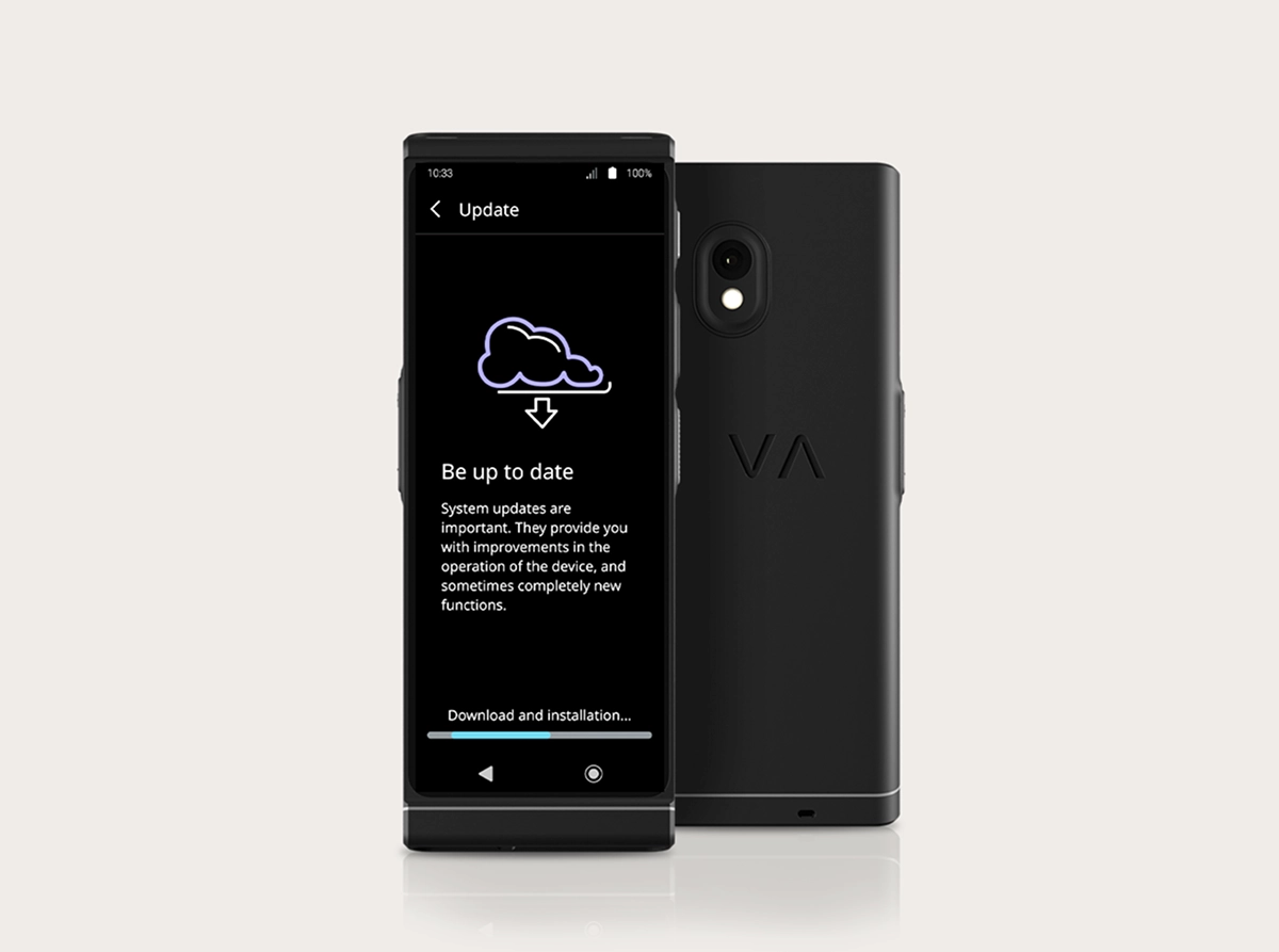 Vasco Translator V4 studijinė nuotrauka, kurioje matoma sistemos atnaujinimo sąsaja. Du juodi įrenginiai padėti vienas šalia kito: vienas nukreiptas į priekį, o kitas – į galą. Ekrane matoma debesies piktograma su atsisiuntimo rodykle, antraštė „Būkite visada atnaujinti“ ir apačioje esanti pažangos juosta su užrašu „Atsisiuntimas ir diegimas...“. Galinėje pusėje matoma dvigubo objektyvo kamera ir reljefinis VA logotipas.