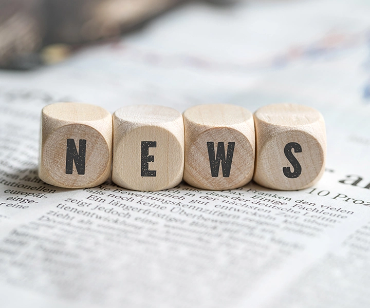 Blokai su užrašu „NEWS“, gulintys ant laikraščio.